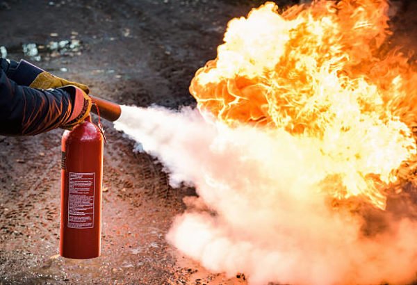 A man using a carbon dioxide fire extinguisher to fight a fire 