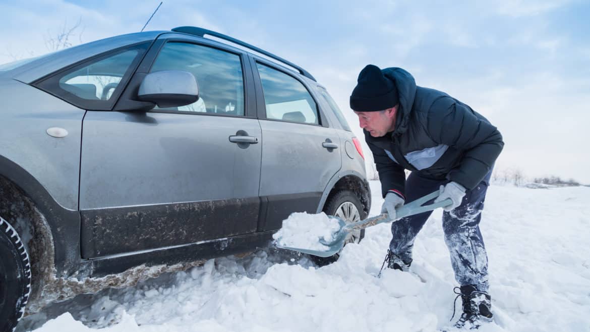 Man shoveling snow to free his stuck car